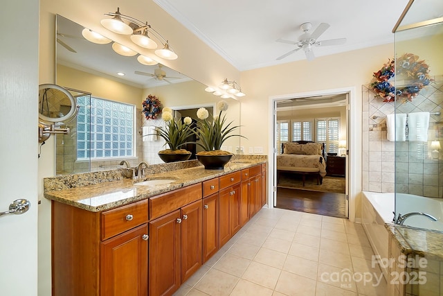 bathroom with tile patterned floors, a relaxing tiled tub, crown molding, and vanity