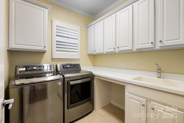 laundry room featuring cabinets, crown molding, sink, light tile patterned floors, and washing machine and dryer