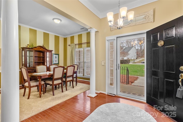 foyer with ornamental molding, decorative columns, hardwood / wood-style flooring, and a notable chandelier