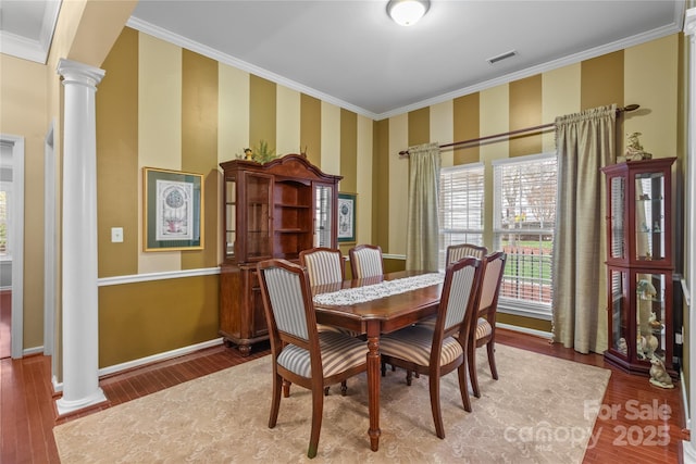 dining space with ornate columns, crown molding, and hardwood / wood-style flooring