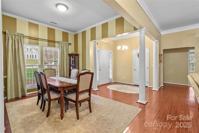 dining room featuring ornate columns, hardwood / wood-style flooring, crown molding, and an inviting chandelier