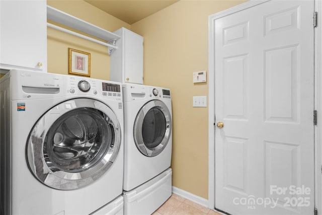 laundry area with light tile patterned flooring, cabinets, and independent washer and dryer