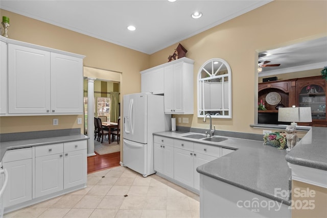 kitchen featuring white cabinetry, white fridge with ice dispenser, ceiling fan, sink, and ornamental molding