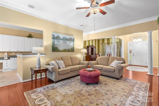 living room featuring ornate columns, light hardwood / wood-style floors, ceiling fan with notable chandelier, and ornamental molding