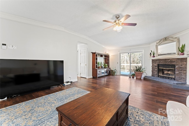 living room featuring crown molding, vaulted ceiling, ceiling fan, a textured ceiling, and a fireplace