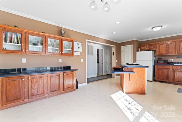 kitchen featuring a kitchen breakfast bar, crown molding, a center island, and white refrigerator