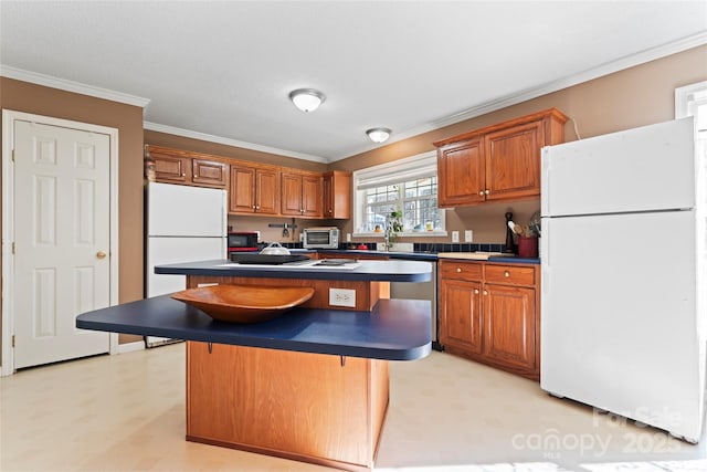 kitchen with a kitchen breakfast bar, white fridge, ornamental molding, and a kitchen island