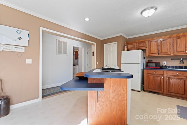 kitchen with a center island, a kitchen breakfast bar, crown molding, white fridge, and a textured ceiling