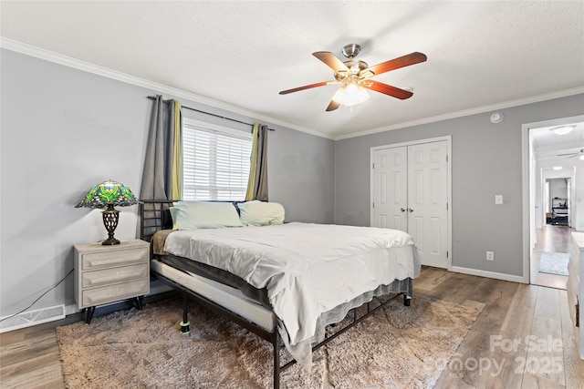 bedroom featuring hardwood / wood-style floors, a closet, ceiling fan, and crown molding