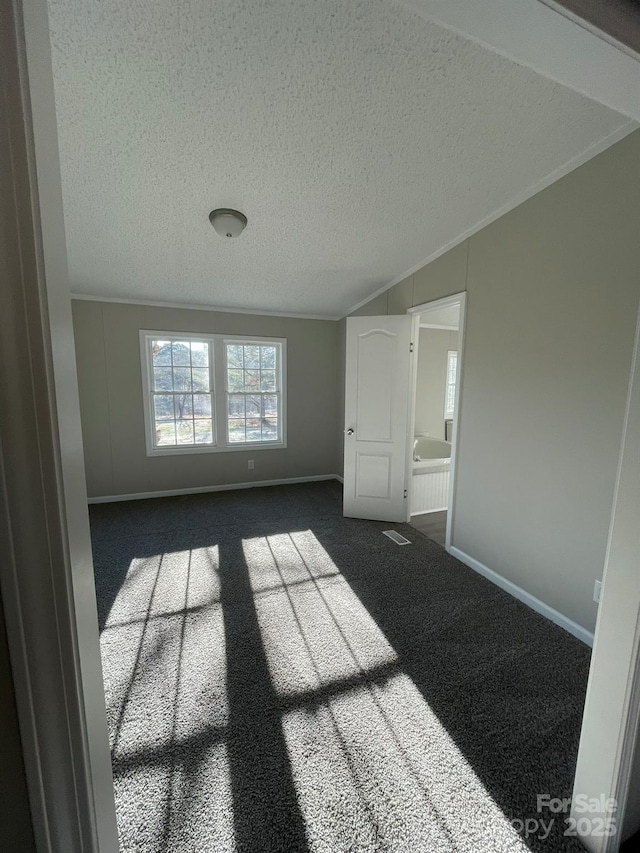 unfurnished room featuring a textured ceiling, dark carpet, and ornamental molding