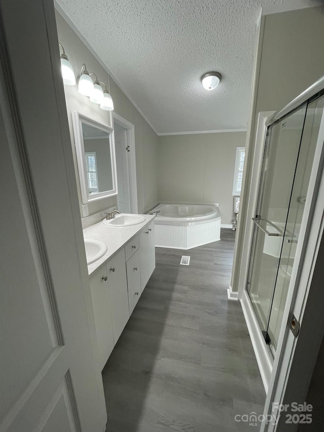 bathroom featuring vanity, shower with separate bathtub, a textured ceiling, and wood-type flooring