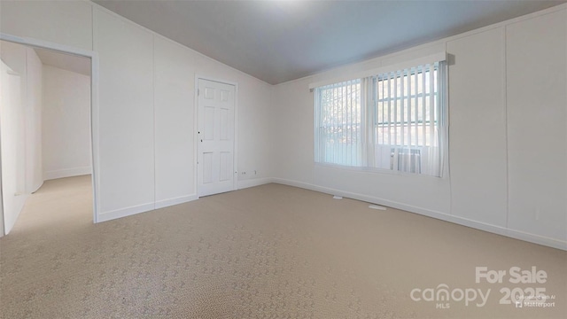 carpeted spare room with vaulted ceiling