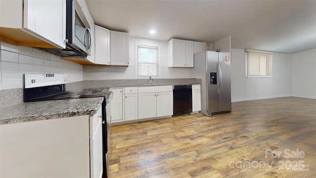 kitchen with sink, light stone countertops, light wood-type flooring, appliances with stainless steel finishes, and white cabinetry