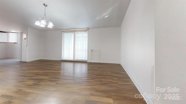 empty room with a chandelier and dark wood-type flooring