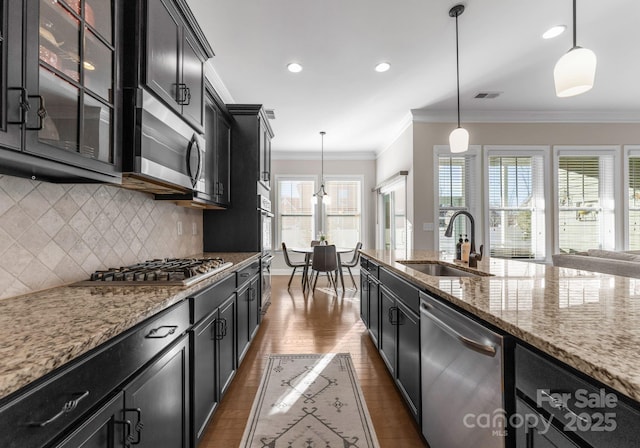 kitchen with pendant lighting, sink, decorative backsplash, light stone countertops, and stainless steel appliances