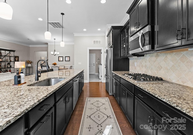 kitchen with sink, tasteful backsplash, a notable chandelier, decorative light fixtures, and appliances with stainless steel finishes