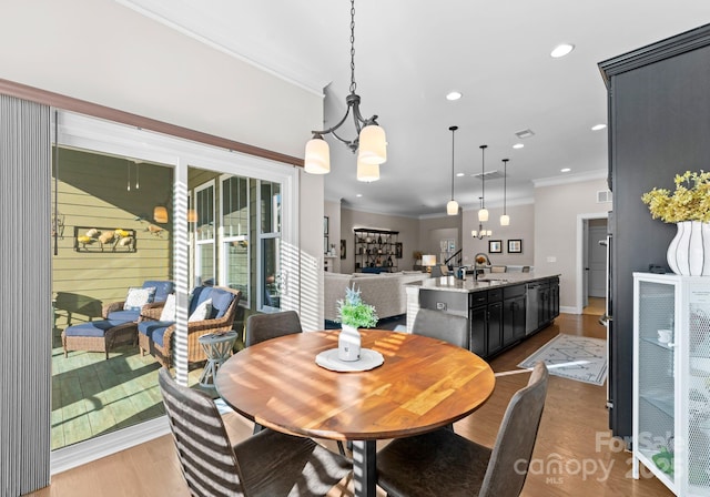 dining area featuring an inviting chandelier, light hardwood / wood-style flooring, ornamental molding, and sink