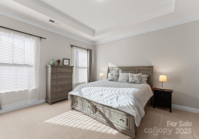 carpeted bedroom with a tray ceiling and crown molding