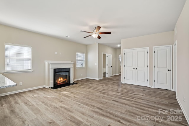 unfurnished living room featuring light wood-type flooring, plenty of natural light, and ceiling fan