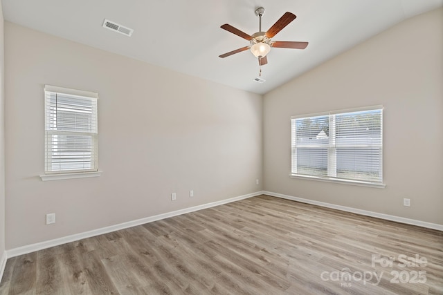 spare room with a wealth of natural light, ceiling fan, lofted ceiling, and light wood-type flooring