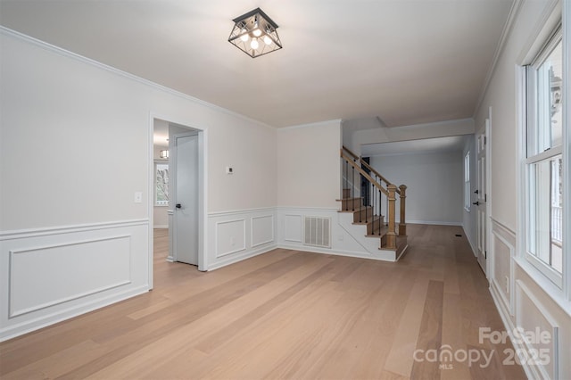 entrance foyer featuring ornamental molding, light hardwood / wood-style floors, and a healthy amount of sunlight