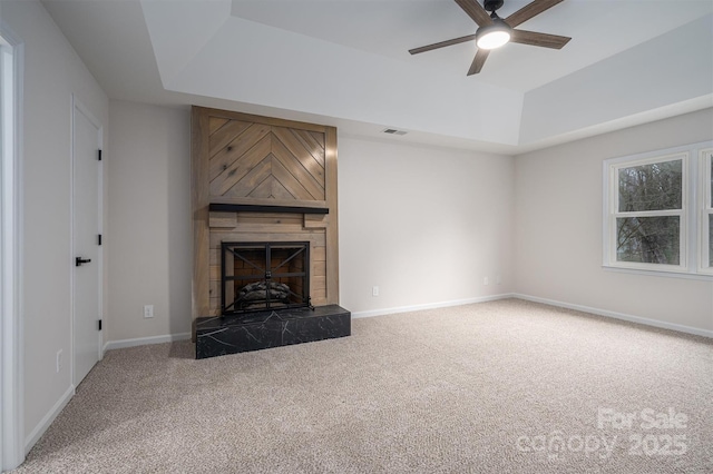 unfurnished living room featuring a large fireplace, carpet floors, and a tray ceiling