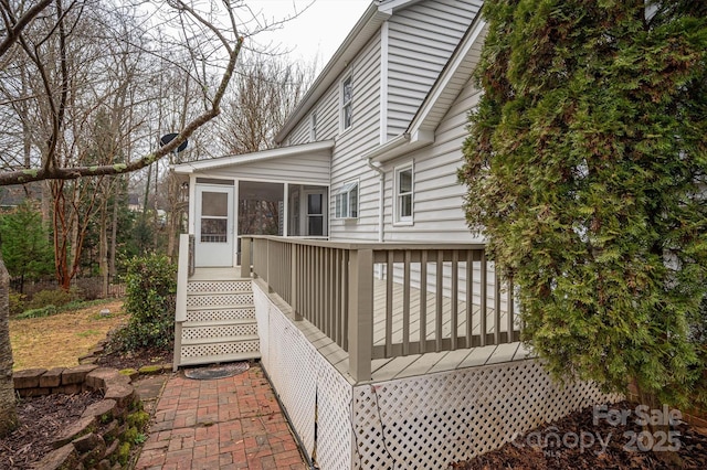 view of side of home featuring a wooden deck and a sunroom