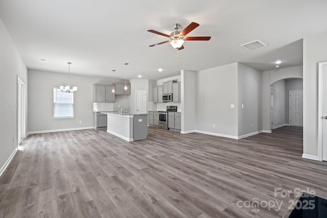 unfurnished living room with ceiling fan with notable chandelier, dark hardwood / wood-style floors, and sink