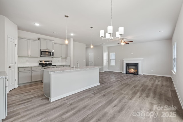 kitchen with gray cabinetry, ceiling fan, stainless steel appliances, pendant lighting, and decorative backsplash