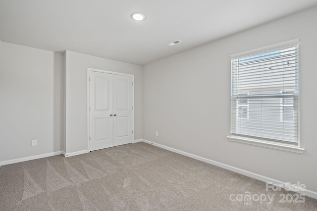 unfurnished bedroom featuring a closet and light colored carpet