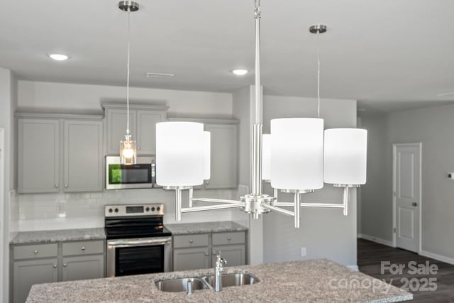 kitchen featuring pendant lighting, light stone countertops, sink, and appliances with stainless steel finishes