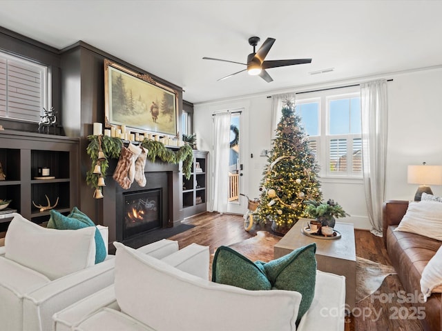 living room with ornamental molding, dark hardwood / wood-style flooring, ceiling fan, and a healthy amount of sunlight