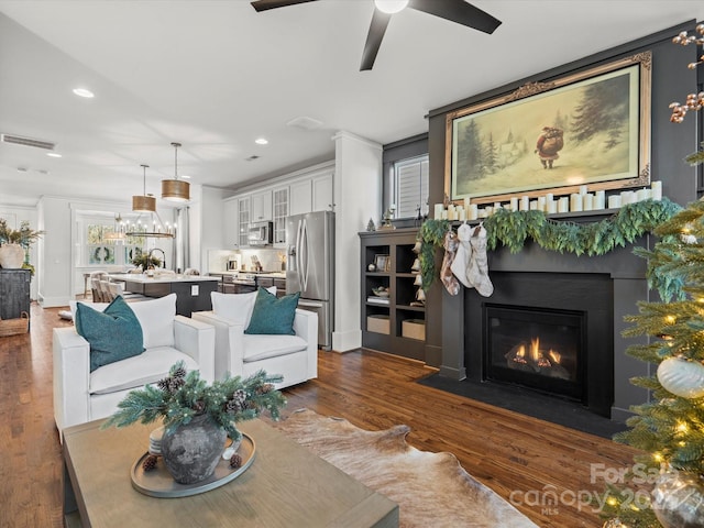 living room featuring dark hardwood / wood-style floors, ceiling fan, and ornamental molding