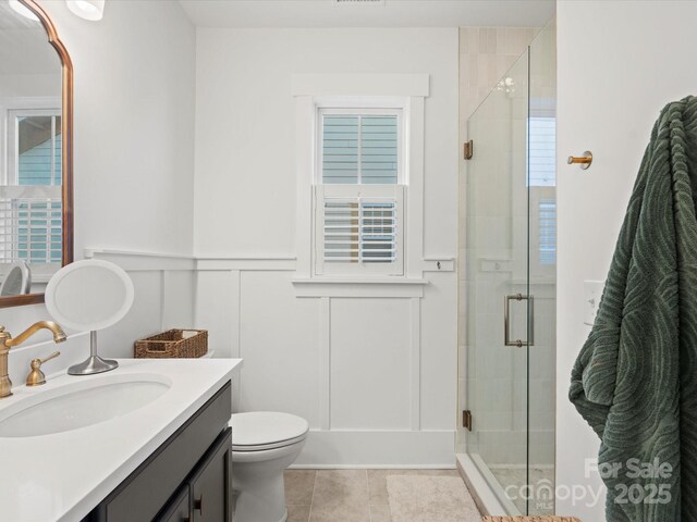 bathroom with tile patterned flooring, a shower with door, vanity, and toilet