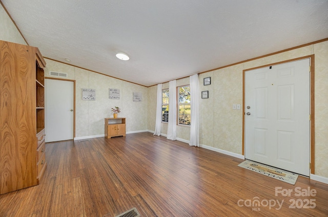 entryway with a textured ceiling, lofted ceiling, dark hardwood / wood-style floors, and crown molding