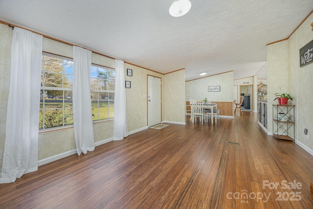 interior space with dark wood-type flooring, a textured ceiling, and ornamental molding