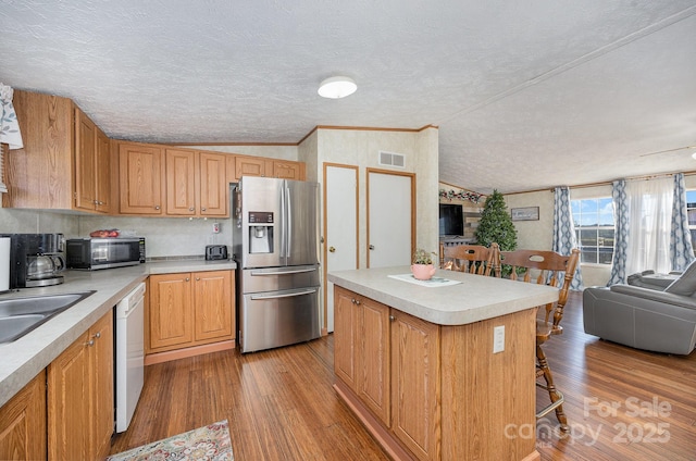 kitchen with appliances with stainless steel finishes, light wood-type flooring, a textured ceiling, a center island, and lofted ceiling