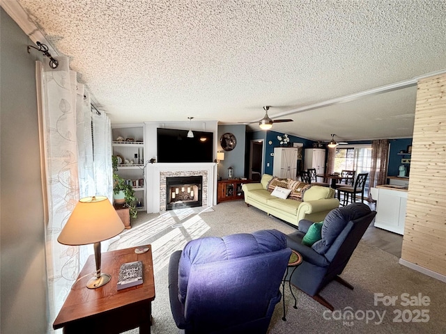 carpeted living room featuring built in features, a textured ceiling, a stone fireplace, and ceiling fan