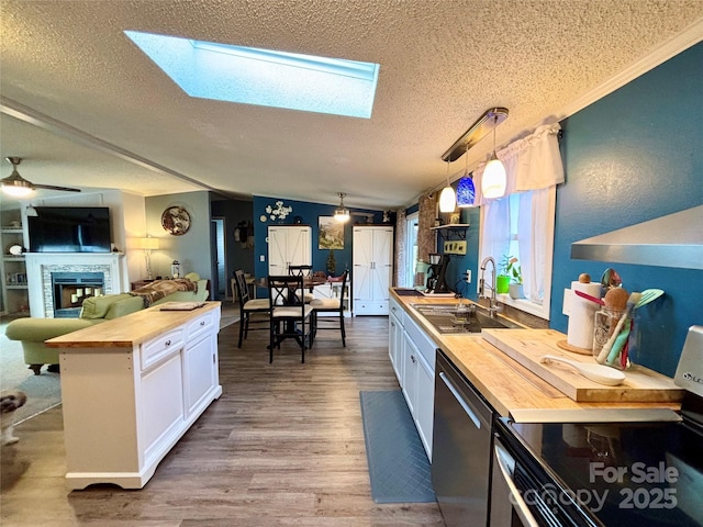 kitchen featuring a skylight, white cabinetry, decorative light fixtures, and wood counters