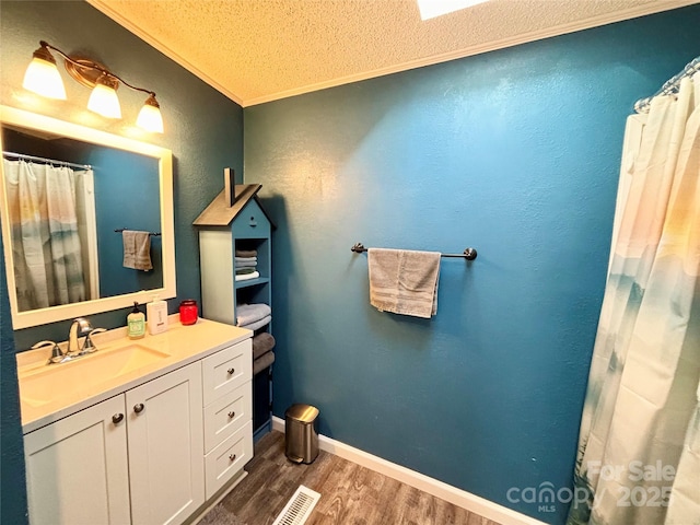 bathroom with crown molding, vanity, wood-type flooring, and a textured ceiling