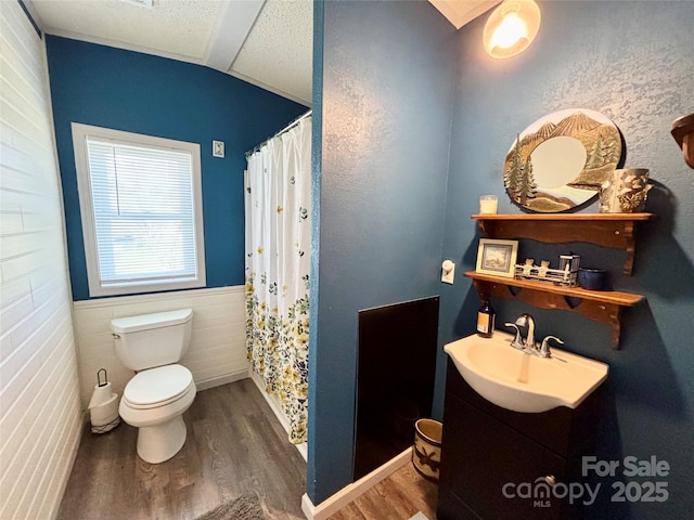 bathroom featuring sink, hardwood / wood-style floors, vaulted ceiling, toilet, and a shower with shower curtain