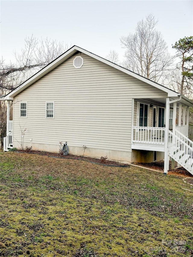 view of home's exterior with covered porch and a lawn