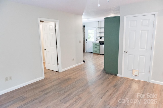 spare room with light wood-type flooring and a textured ceiling