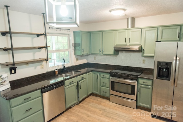 kitchen featuring a textured ceiling, appliances with stainless steel finishes, light hardwood / wood-style floors, sink, and green cabinetry