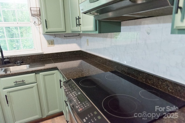 kitchen featuring range, extractor fan, dark stone counters, and green cabinetry