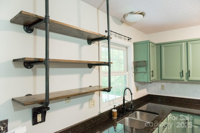 kitchen with decorative backsplash, dark stone countertops, green cabinetry, a textured ceiling, and sink