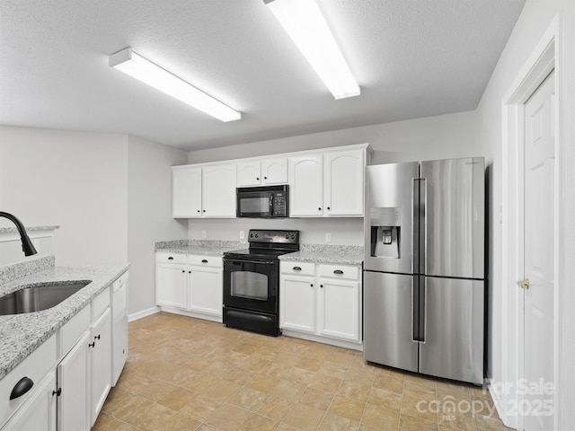 kitchen with black appliances, white cabinetry, light stone counters, and a sink