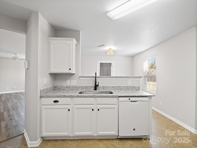 kitchen featuring baseboards, light stone counters, white dishwasher, white cabinetry, and a sink