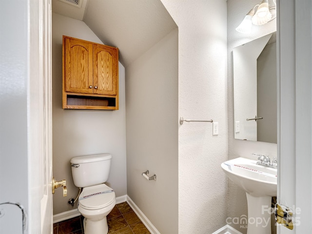 half bathroom featuring lofted ceiling, tile patterned floors, toilet, and baseboards