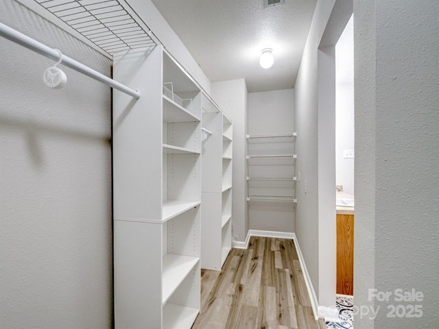 spacious closet with light wood-style flooring and visible vents